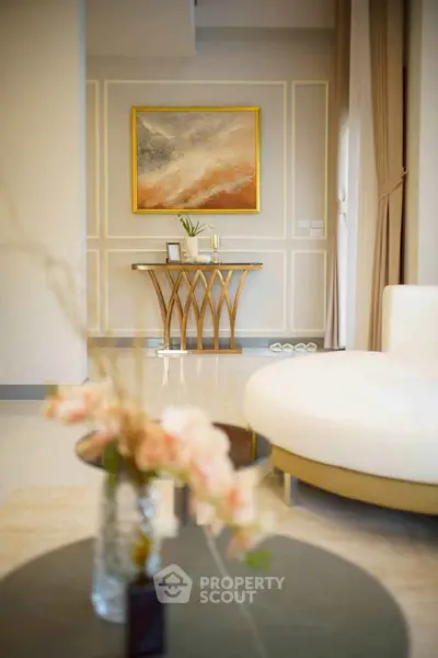 Elegant living room with modern decor and stylish furniture, featuring a large painting and chic table.