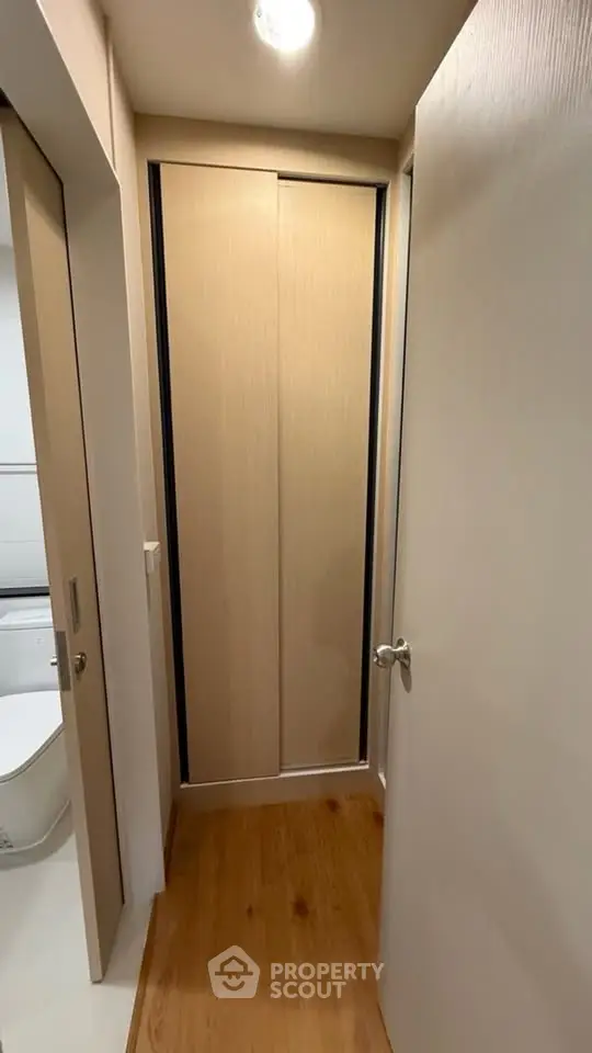 Compact hallway with wooden flooring and sliding closet doors in modern apartment.