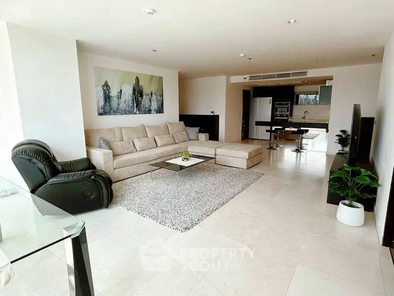 Spacious modern living room with open kitchen, elegant decor, and ample natural light.
