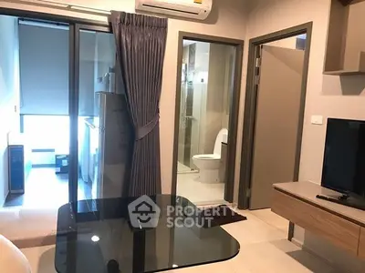 Modern apartment interior with glass dining table, TV, and view into bedroom and bathroom.
