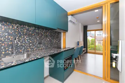 Modern kitchen with terrazzo countertops and open layout leading to a bright living area with balcony.