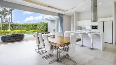 Luxurious open-plan kitchen and dining area with pool view, modern furniture, and sleek design.
