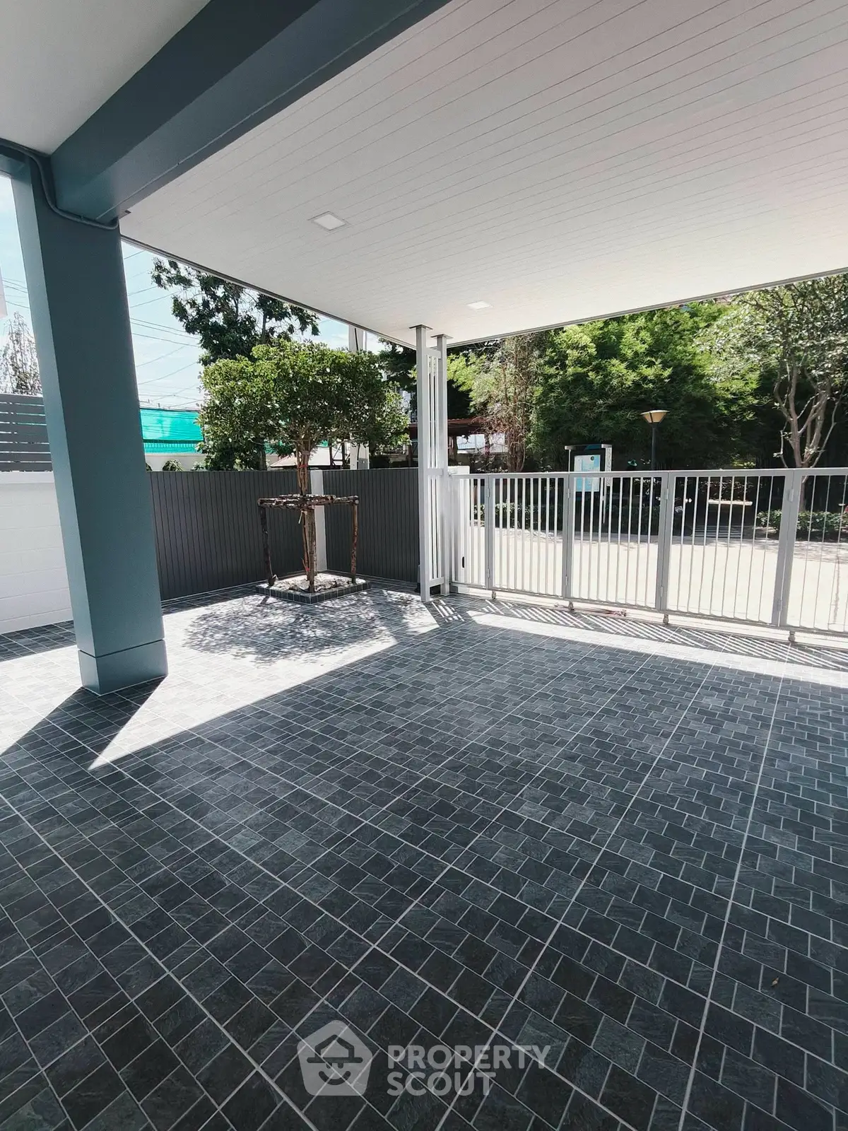 Spacious outdoor patio with modern tile flooring and partial garden view.