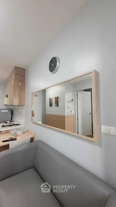 Modern living room with sleek kitchen and stylish decor, featuring a large wall mirror and contemporary furniture.