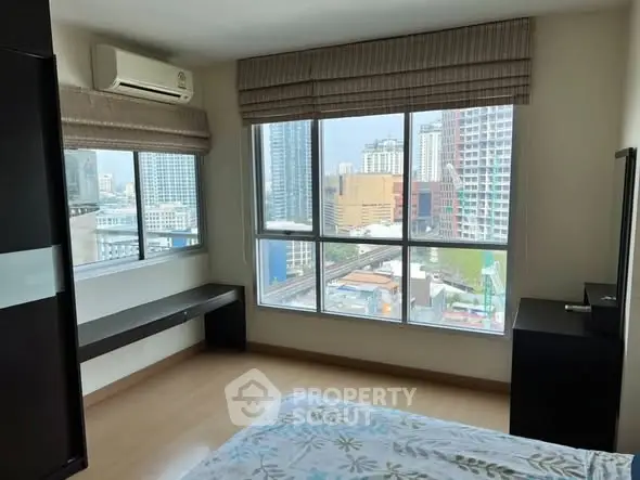 Spacious bedroom with large windows offering stunning city views in a modern high-rise apartment.