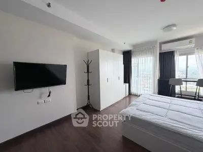 Modern bedroom with sleek design and city view, featuring a wall-mounted TV and stylish wardrobe.