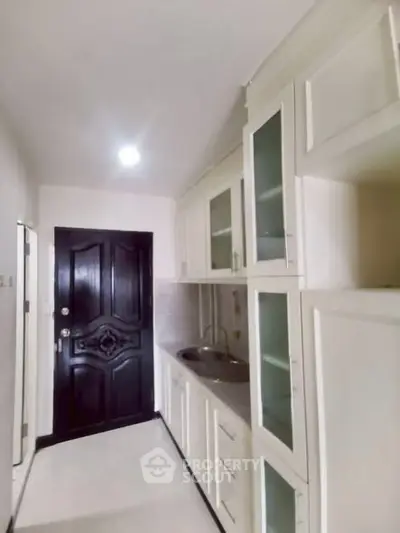 Compact kitchen with white cabinets and sleek black door