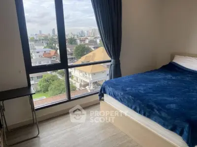 Cozy bedroom with large window offering stunning city views, featuring a comfortable bed and sleek wooden flooring.