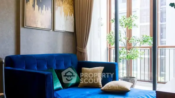 Luxurious living room with blue sofa and large windows opening to a balcony.