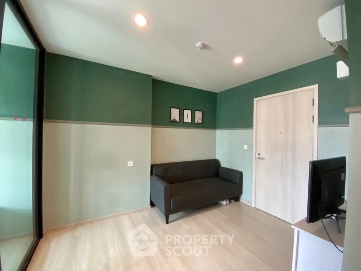 Modern living room with green accent walls and sleek black sofa