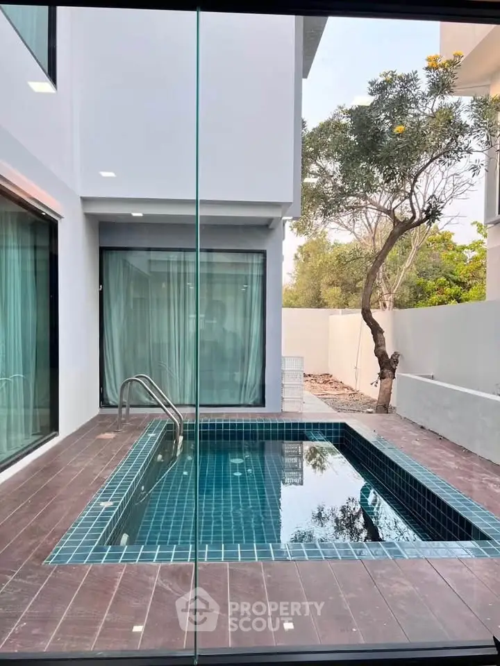 Modern home with private pool and glass walls, offering a serene outdoor retreat.