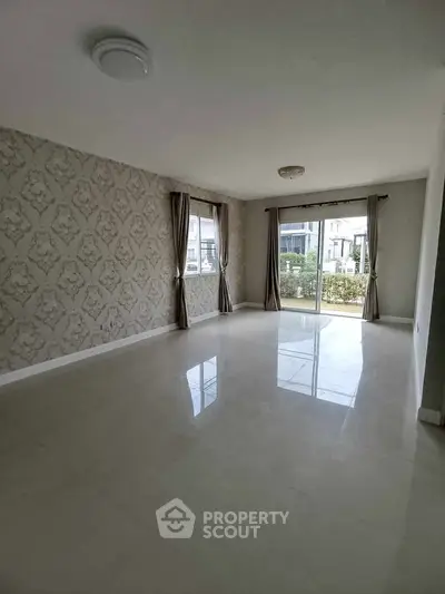 Spacious living room with elegant wallpaper and large windows offering natural light.