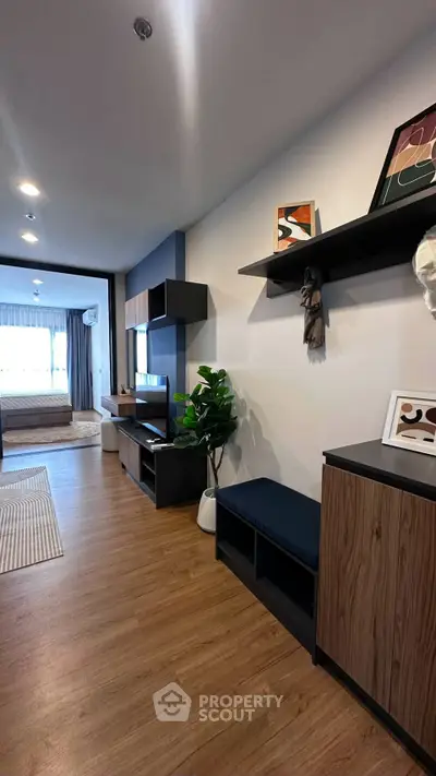 Modern living room with stylish decor and open view to bedroom, featuring wooden flooring and contemporary furniture.