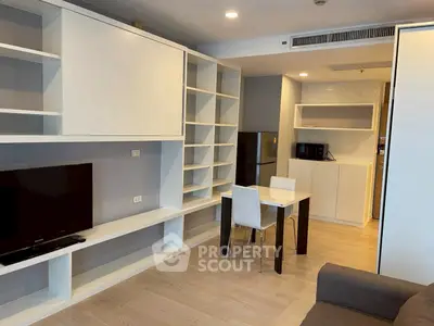Modern living room with built-in shelves and compact dining area in a stylish apartment.