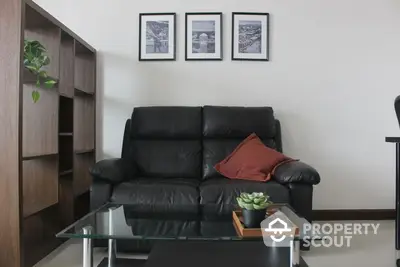 Elegant living room with a plush black leather sofa, glass coffee table, and chic wall art, perfect for modern urban living.