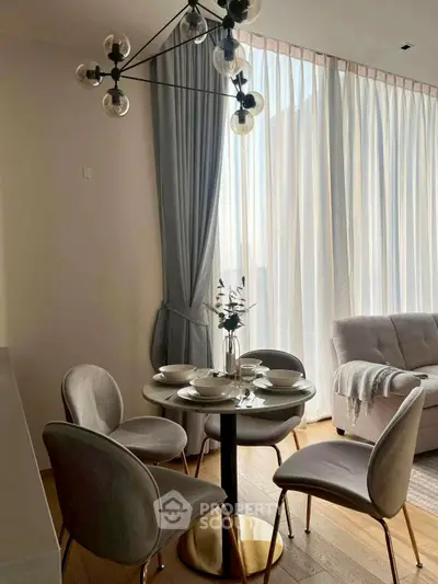 Elegant dining area with modern chandelier and cozy seating in a sunlit room.