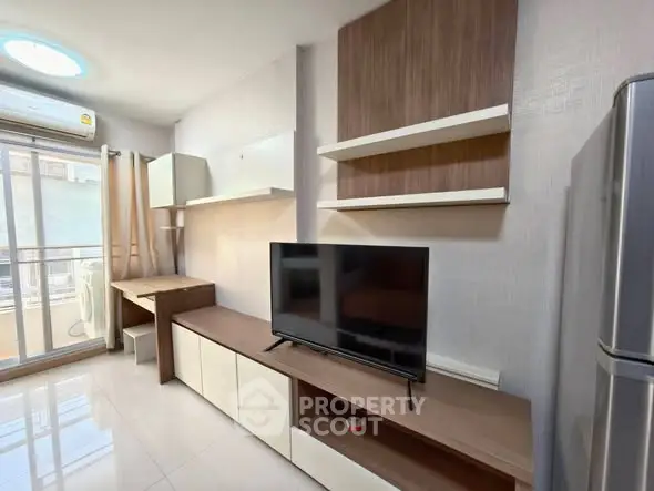 Modern living room with TV, shelves, and balcony access in bright apartment.