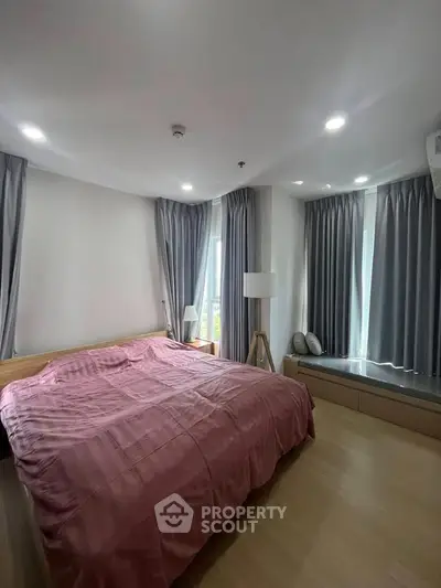 Spacious bedroom with modern decor and large windows for natural light.