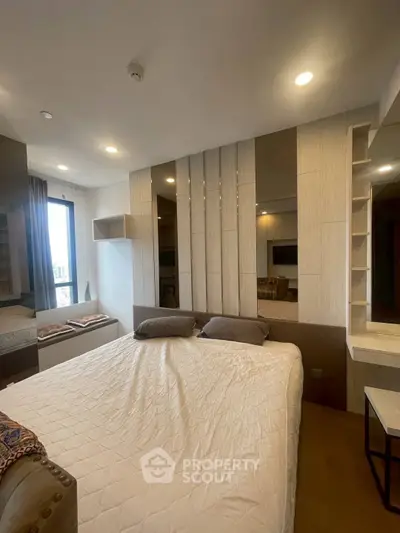 Modern bedroom with stylish decor and large window offering natural light.