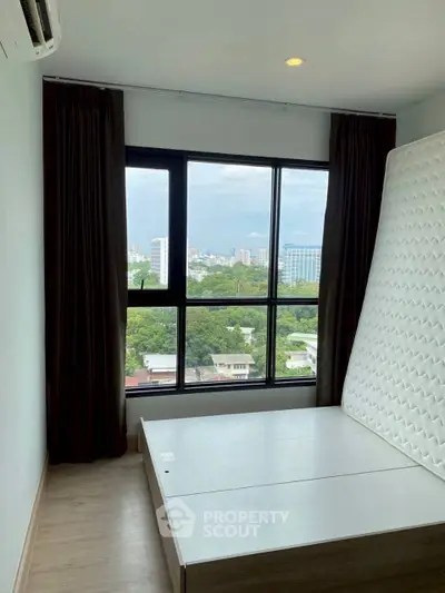 Bright bedroom with large window offering stunning city view and natural light.