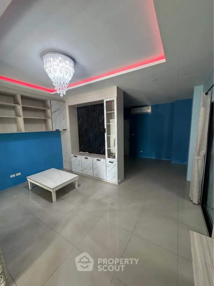 Spacious living room with modern chandelier and built-in shelving, perfect for stylish living.