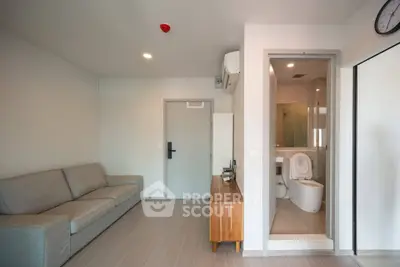 Modern apartment interior with cozy living room and adjacent bathroom, featuring sleek design and neutral tones.