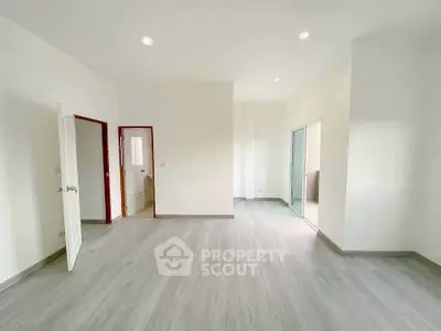 Spacious empty room with modern flooring and white walls, ready for customization.