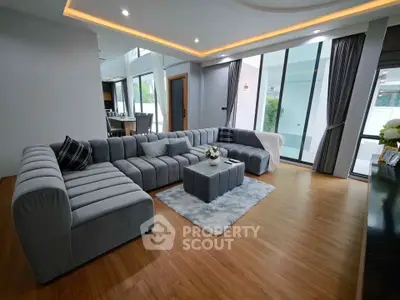 Spacious modern living room with large sectional sofa and floor-to-ceiling windows