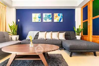 Stylish living room with modern gray sectional sofa, vibrant blue accent wall, and chic decor elements.
