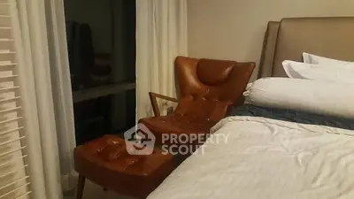 Cozy bedroom with stylish leather chair and ottoman beside a comfortable bed.