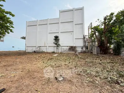 Spacious plot with potential for development, featuring a large white building and open land.