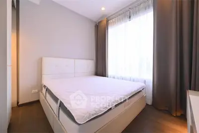 Spacious bedroom with large window and elegant curtains in modern apartment.