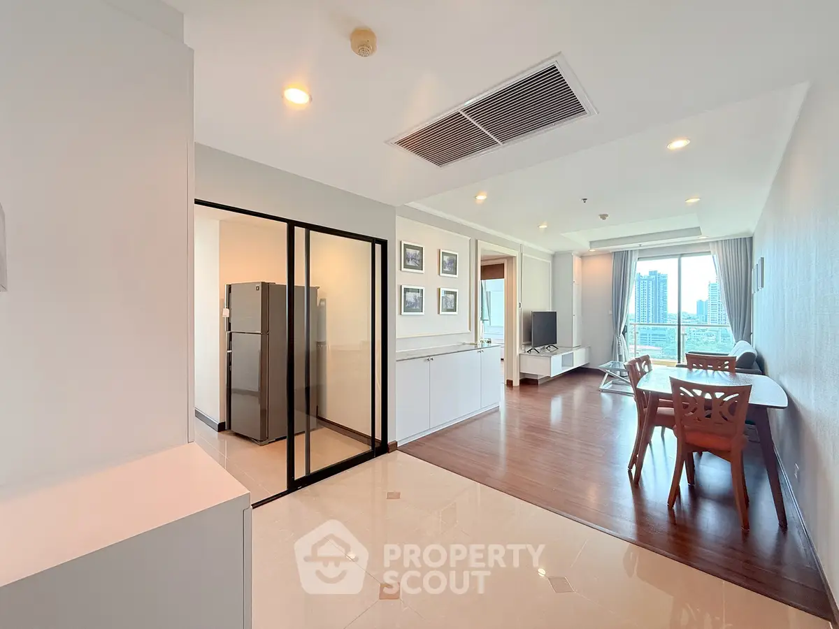 Spacious modern living room with dining area and city view, featuring sleek wooden flooring and contemporary furniture.