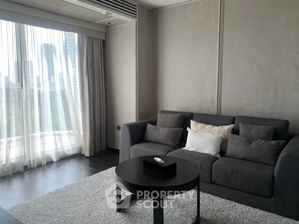 Modern living room with city view, featuring a sleek gray sofa and elegant decor.