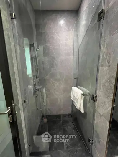 Luxurious modern bathroom with sleek glass shower enclosure and elegant marble walls.