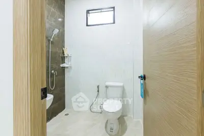 Modern bathroom with sleek design and neutral tones, featuring a shower and toilet.