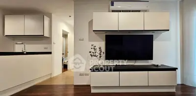 Modern living room with sleek cabinetry and wall-mounted TV, featuring minimalist design and warm lighting.