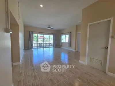 Spacious living room with large windows and tiled flooring, offering ample natural light and a serene view.