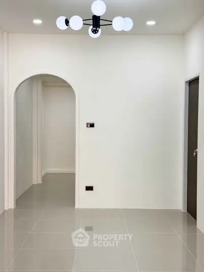 Minimalist interior with modern lighting and archway, showcasing sleek tile flooring and neutral walls.