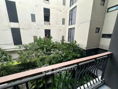 Charming balcony view overlooking lush greenery in modern apartment complex.