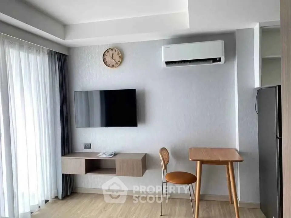 Modern living room with wall-mounted TV and air conditioning, featuring minimalist furniture and natural light.
