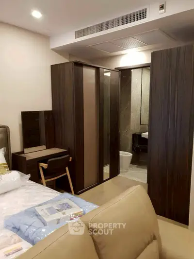 Modern bedroom with sleek furniture and ensuite bathroom in luxury apartment.
