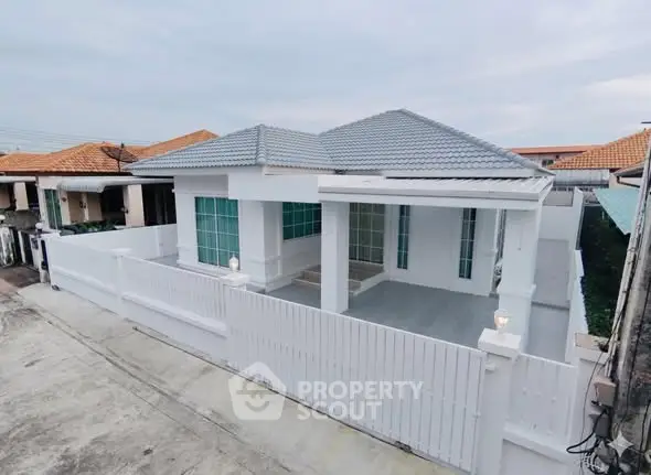 Charming single-story white house with modern design and spacious front yard.