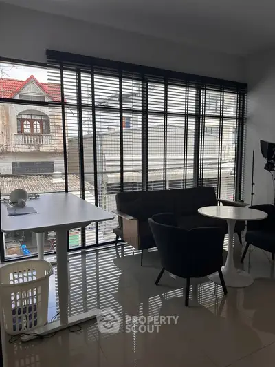 Modern living room with large windows and stylish furniture in urban apartment.