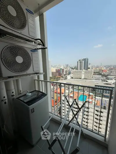 High-rise balcony with city view, featuring air conditioning units and laundry area.