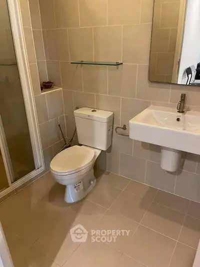 Modern bathroom with sleek fixtures and neutral tiles, featuring a glass shower enclosure.