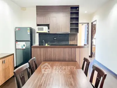 Modern kitchen with wooden cabinets and dining area in a cozy apartment.