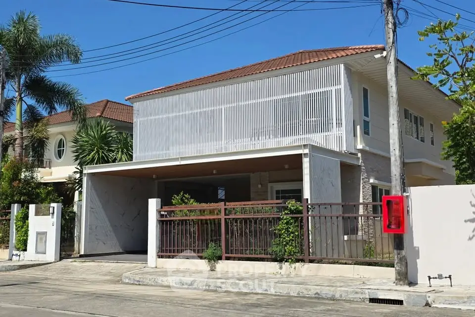 Modern two-story house with sleek design and gated entrance in a suburban neighborhood.