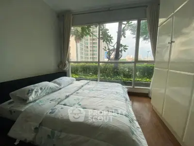 Cozy bedroom with large window offering a lush garden view in a modern apartment.