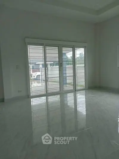Spacious empty room with large windows and glossy tiled floor
